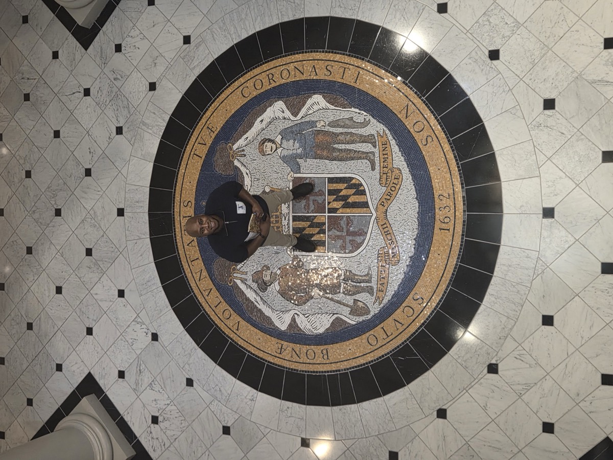 Manny McDaniel of Sennel Gardens standing on the Maryland seal at the State House